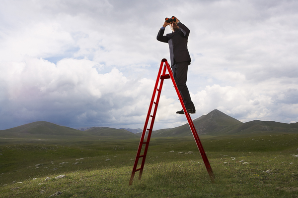 Businessman on ladder looking through binoculars