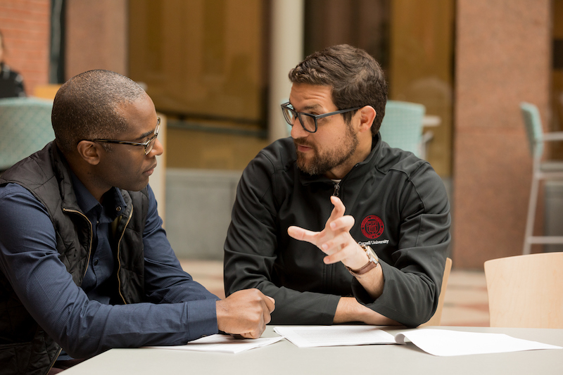 Two men sitting at a table talking in the atrium