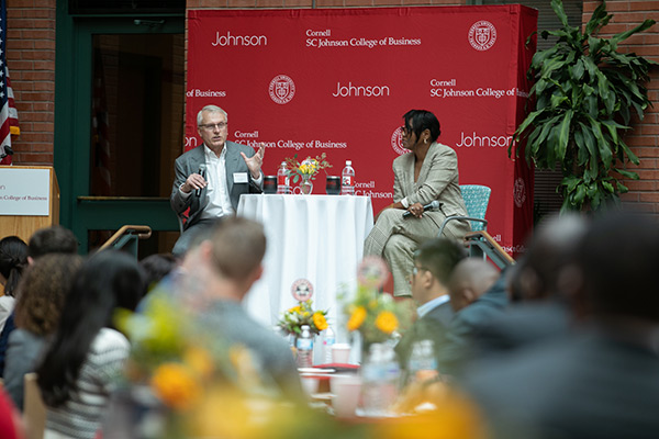 Larry Ruff and Cynthia Saunders-Cheatham seated on a stage and speaking to a room full of people