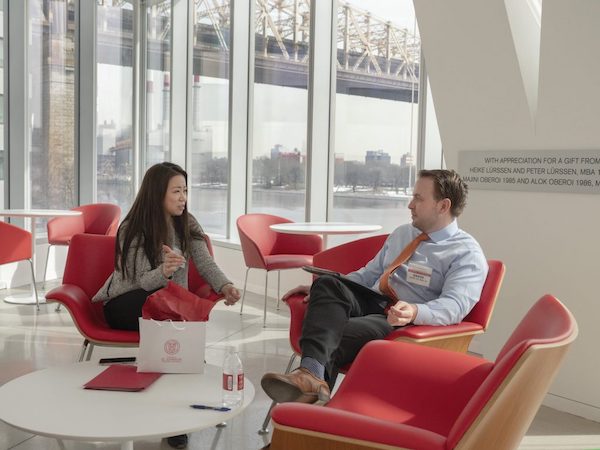 A man speaks with a woman in a conference area