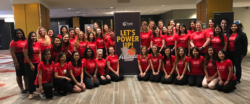 A large group of women with a sign that says Let's Power Up