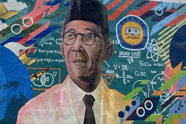 A mural featuring the head of an Indonesian man with glasses, wearing a traditional black peci cap, white jacket and black tie surrounded by colorful educational symbols from math and science.