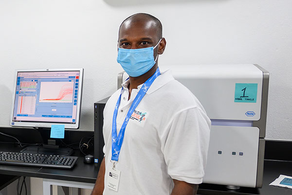 Pradeep Ambrose standing in a lab in front of lab equipment on a counter behind him