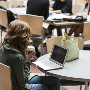 Student working on a laptop in Dyson Atrium in Sage Hall