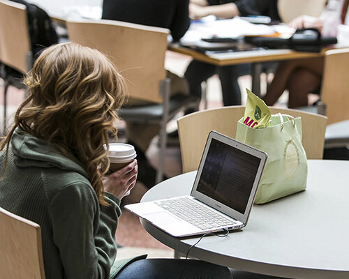 Student working on a laptop in Dyson Atrium in Sage Hall