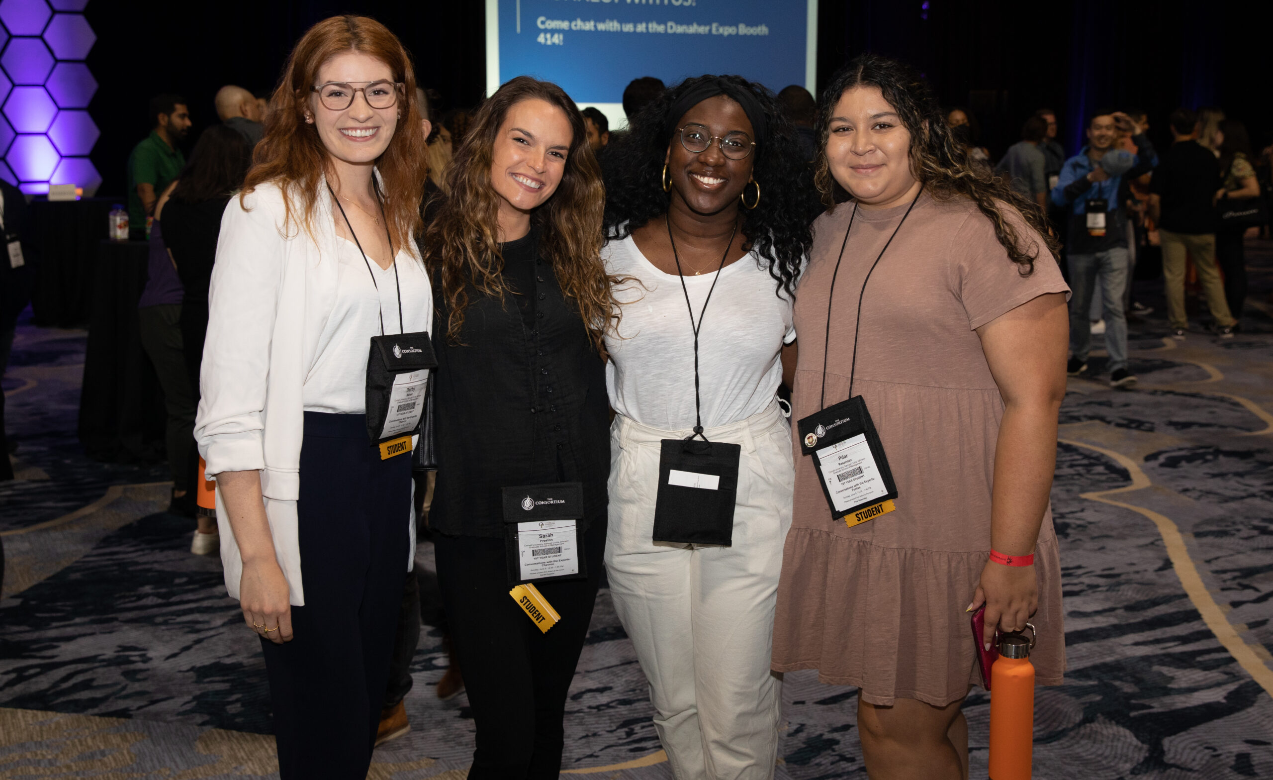 Four women standing together smiling at the camera.