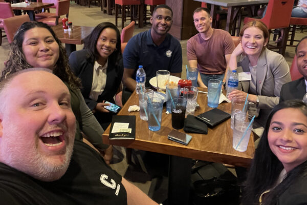 People sitting around a table posting for a selfie.