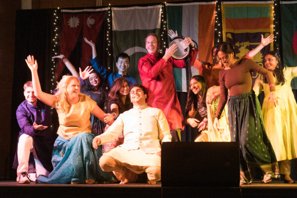 Dean Nelson and Johnson students dancing on a stage in traditional Indian clothing.