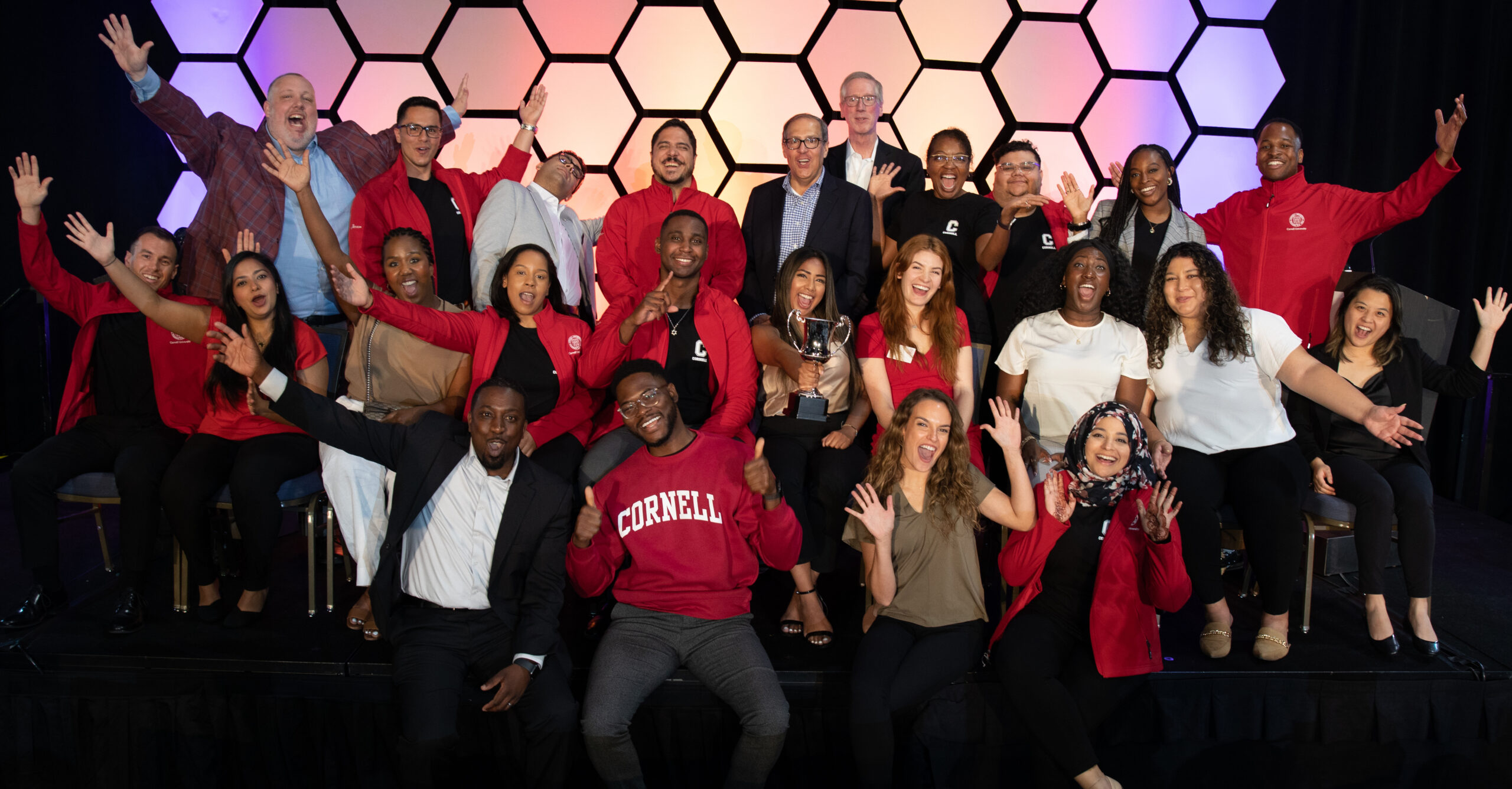 Group of Cornell MBA students posing in funny positions celebrating the winning of the T.E.A.M. trophy at Consortium Orientation Program in 2022.