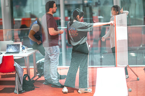 Four students collaborate in front of a whiteboard.