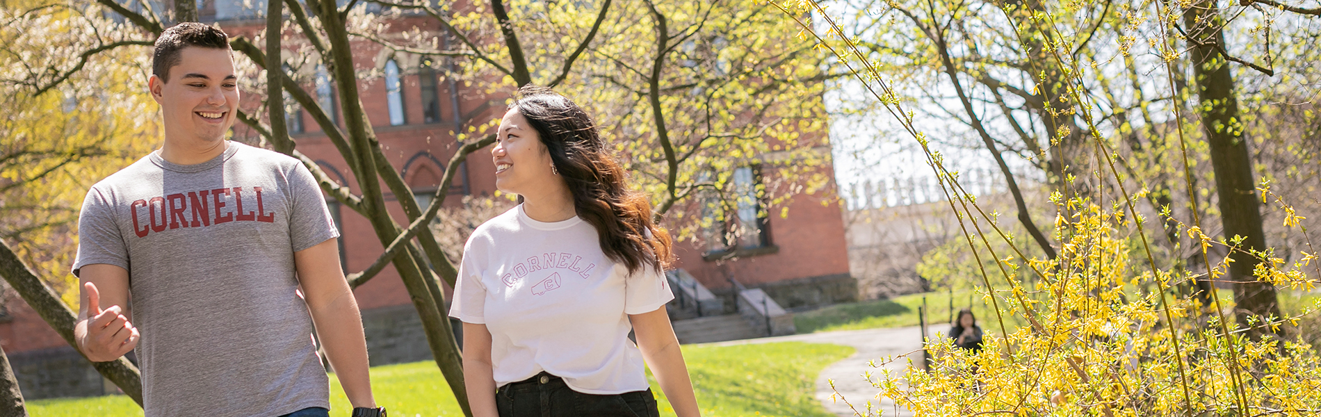 Two students in t-shrits walk outside on the Cornell University campus