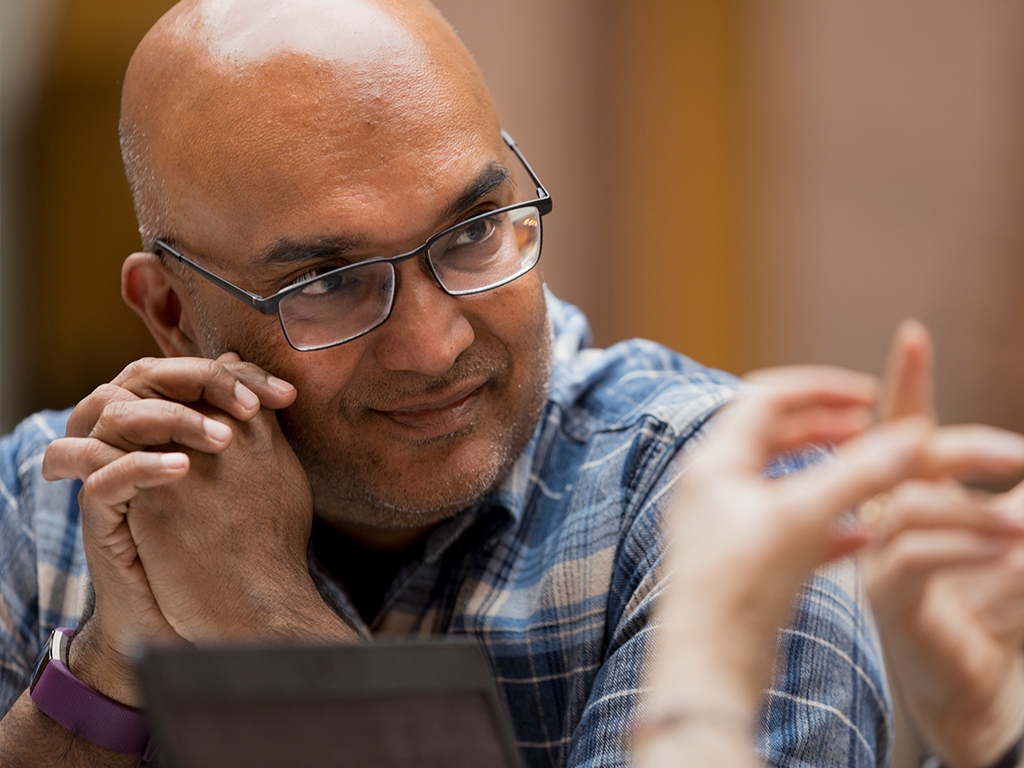 Natarajan leans his head on his hands and look to the right.