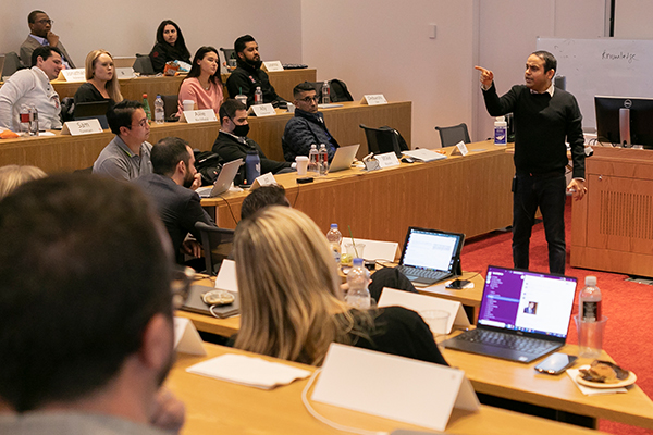 A professor stands at the front of the room in a tiered classroom.