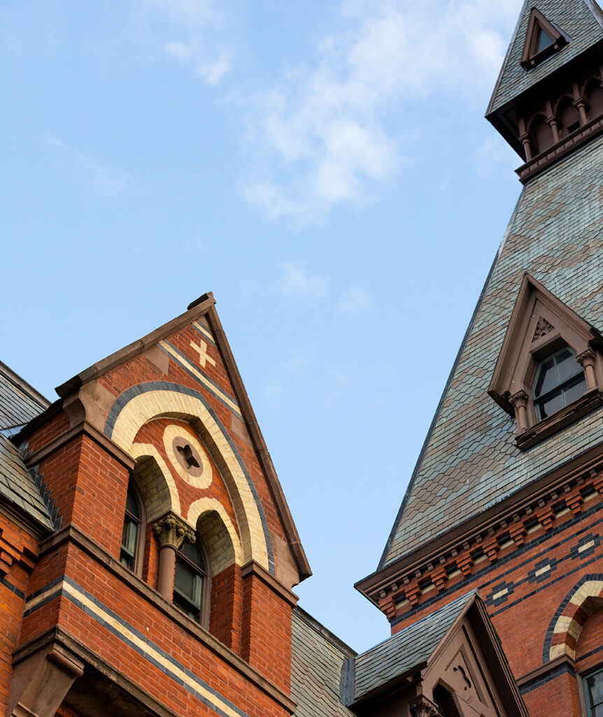 Top of Sage Hall’s brick facade with a blue sky in the background.