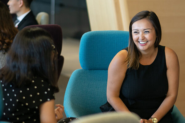 Two people sitting in soft seating smiling and chatting.