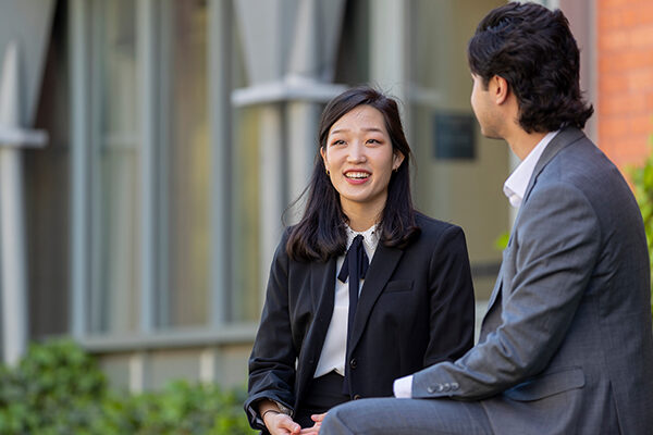 Two people sitting outside in business attire.