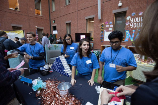 Students standing at table in matching shirts promoting Nair products at Sage Hall