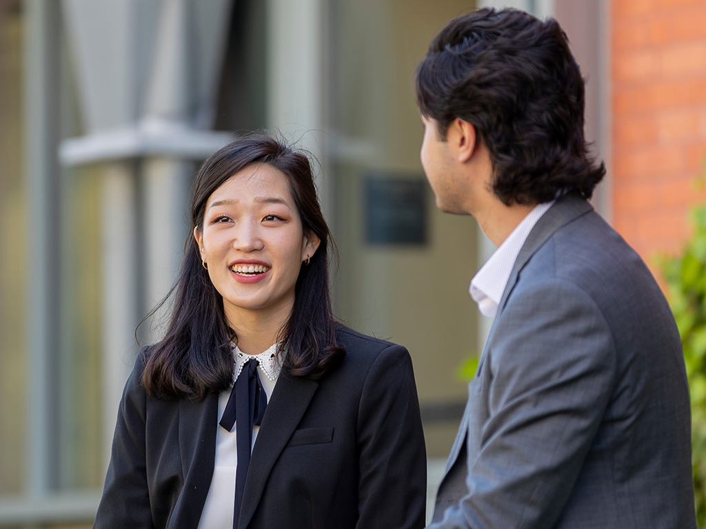 Two people in business attire sit outside.