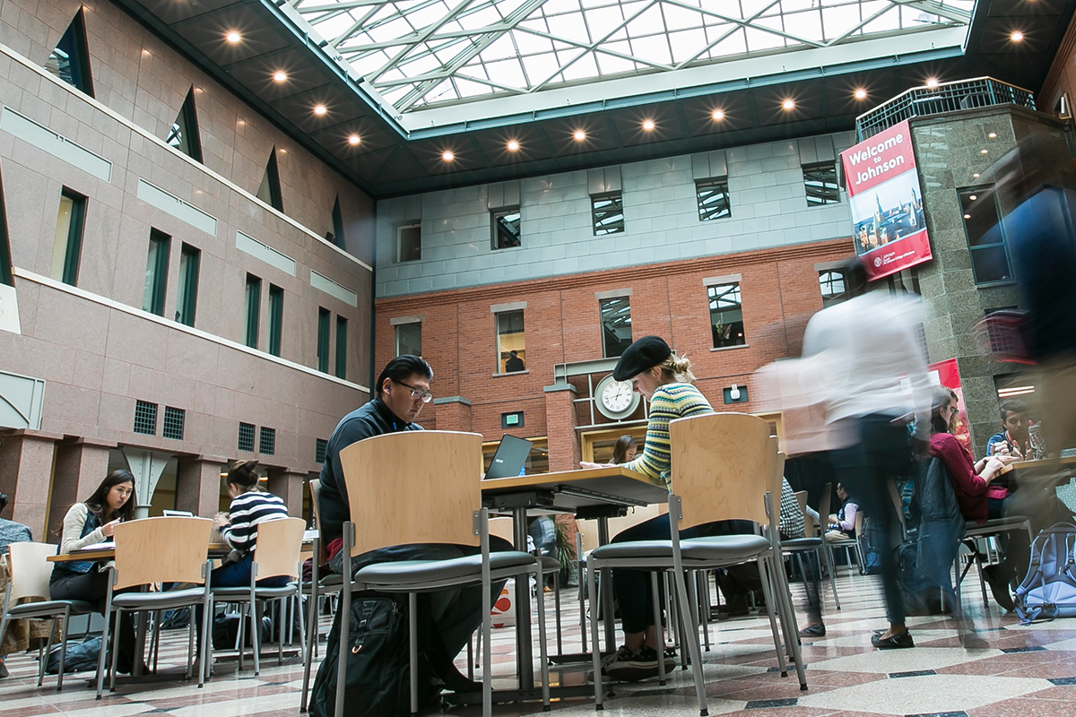 People sitting at tables in the Sage Hall atrium.