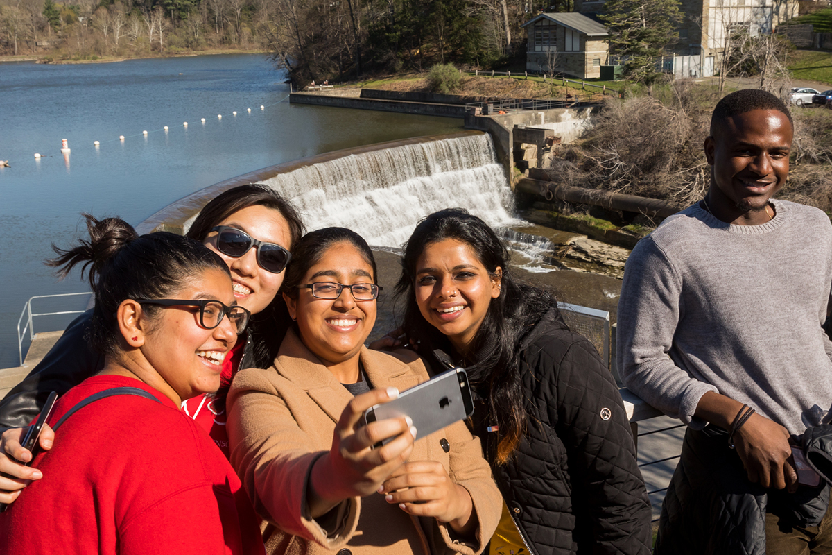 Students pose taking a selfie in front of a small waterfall.