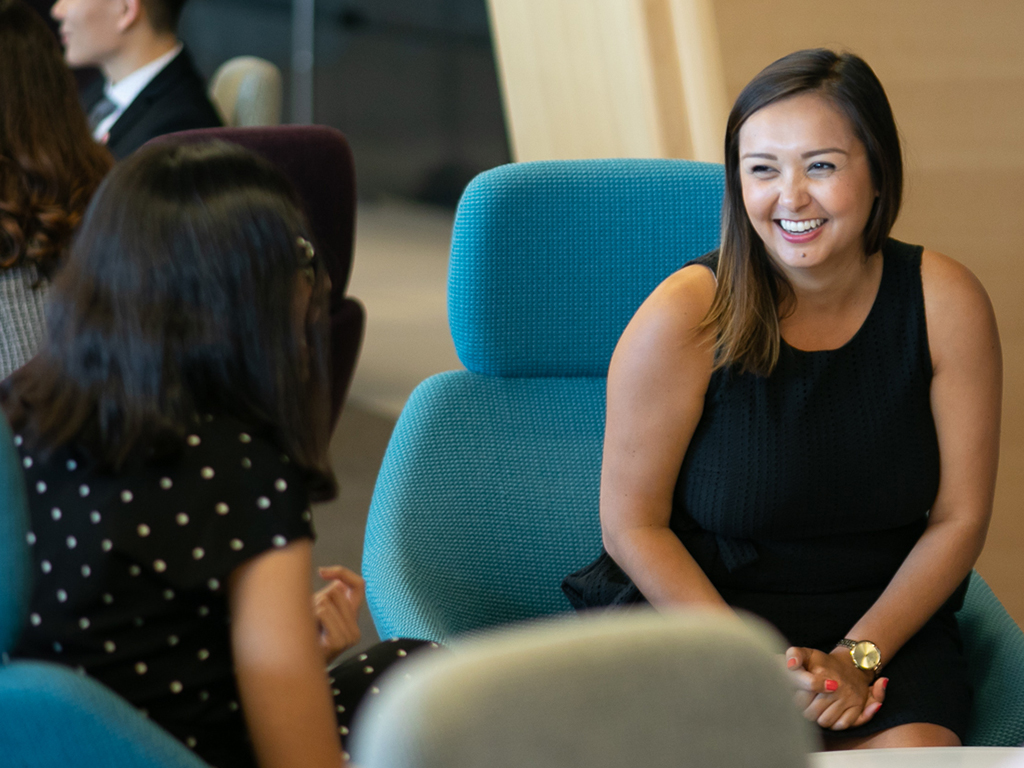 Two women sitting in soft seating smiling at each other.