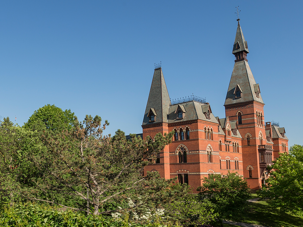 Sage Hall visible beyond green treetops.