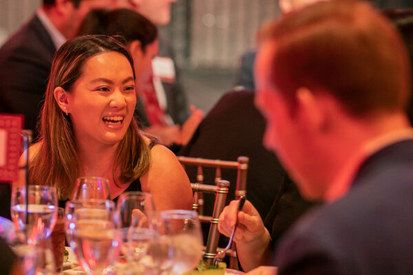 A woman laughs while sitting at a table at a formal dinner.