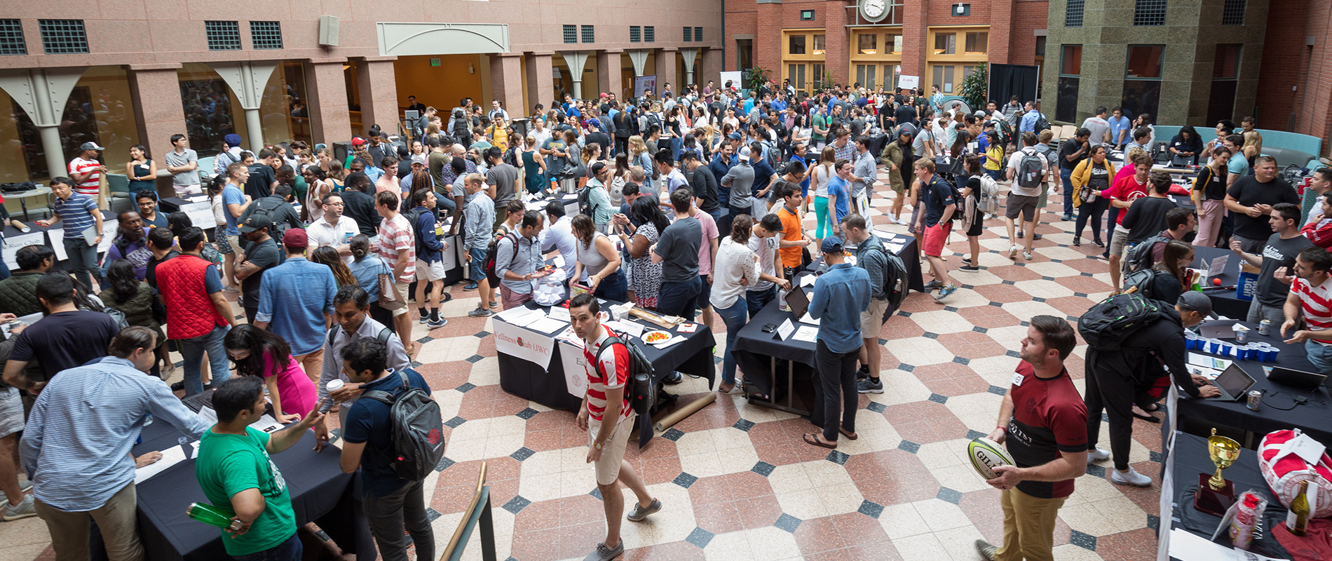 People visiting tables set up at a club fair in the Sage Hall atrium.