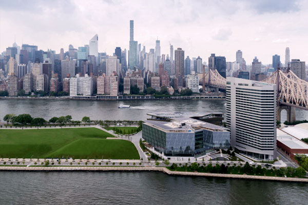 Aerial view of the Cornell Tech campus on Roosevelt Island with the Manhattan skyline visible across the river.