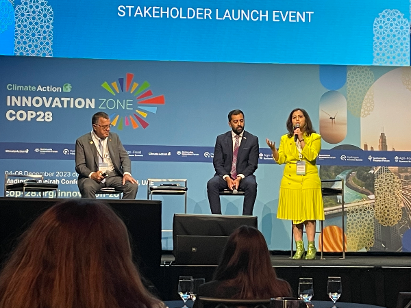 Kehkashan Basu, MBA '24, stands on stage holding a microphone.