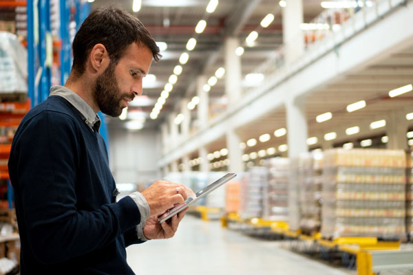 A man works on a tablet in a warehouse.