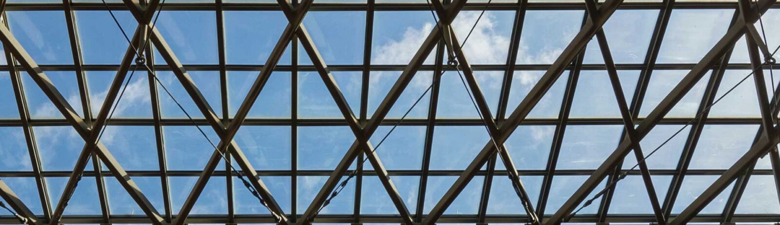 Blue sky and small white clouds visible through the glass ceiling of the Sage Hall atrium.