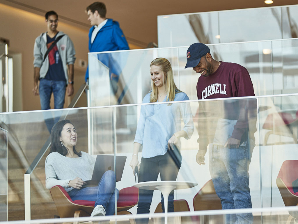 Students smile and laugh while on a tiered soft-seating area.