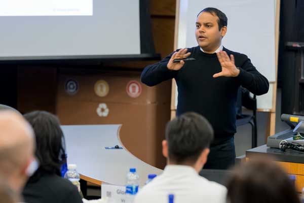 A professor stands at the front of a classroom with a clicker in his hands.