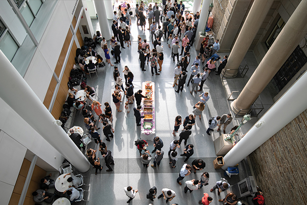 View from above of people milling about a buffet table and chatting in small groups.