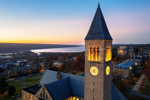 McGraw Tower at sunset with a lake in the background.
