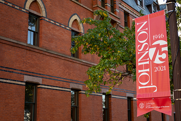 Red flag featuring the Johnson School 75th Anniversary identifier with Sage Hall visible in the background.