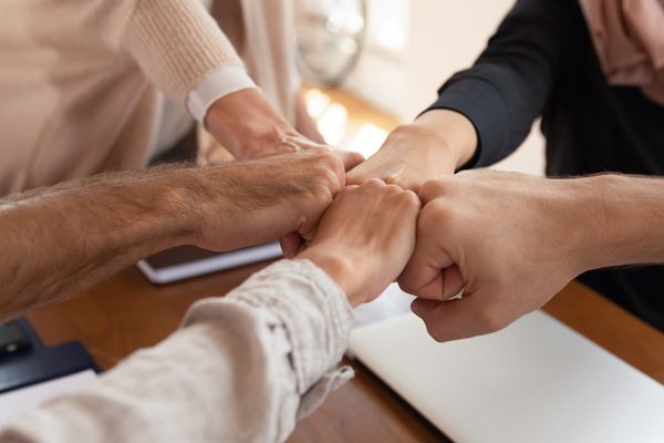 photo of five different people's fists joined together in a fist bump.