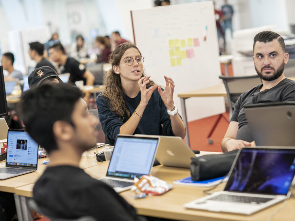 Group of students sitting at shared table studying technology and conversing