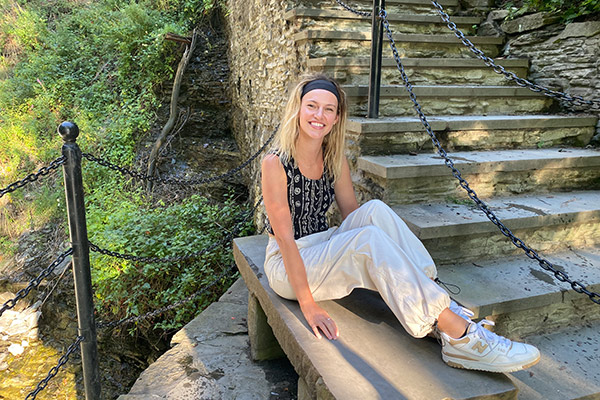 Kyra Stiggelbout sitting on a stone step wearing New Balance sneakers.