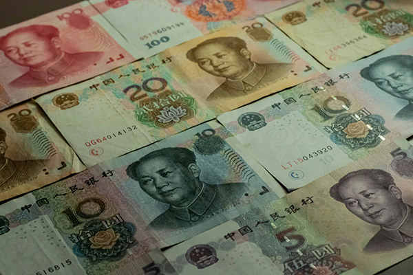A tabletop covered with lots of different Chinese Renminbi bills.