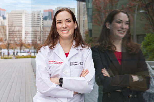 Female student with a lab coat leaning against a window.