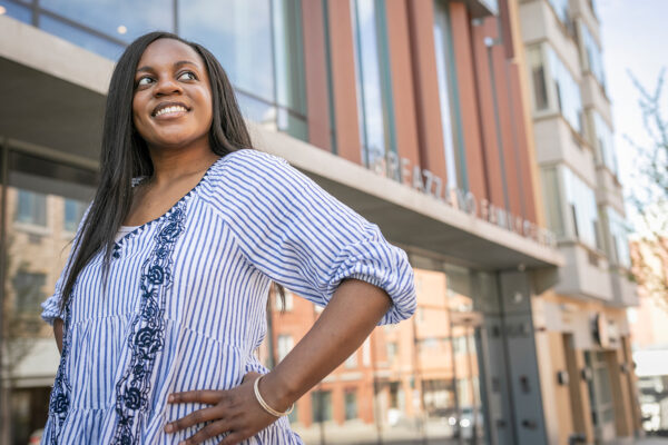 A female student standing with her hand on her hip in front of Breazzano Family Center building.