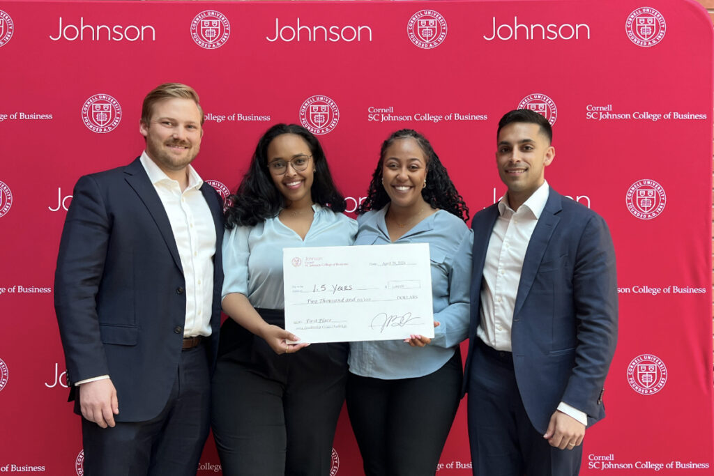 The four person winning team of the 2024 Leadership Crisis Challenge stand together in front of a Cornell branded backdrop.