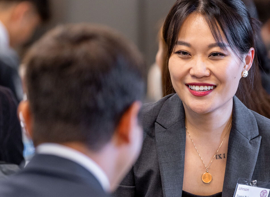 A woman in business attire speaks with a man, also in business attire.