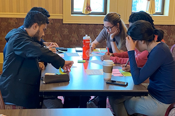 Students sit around a table working collaboratively.