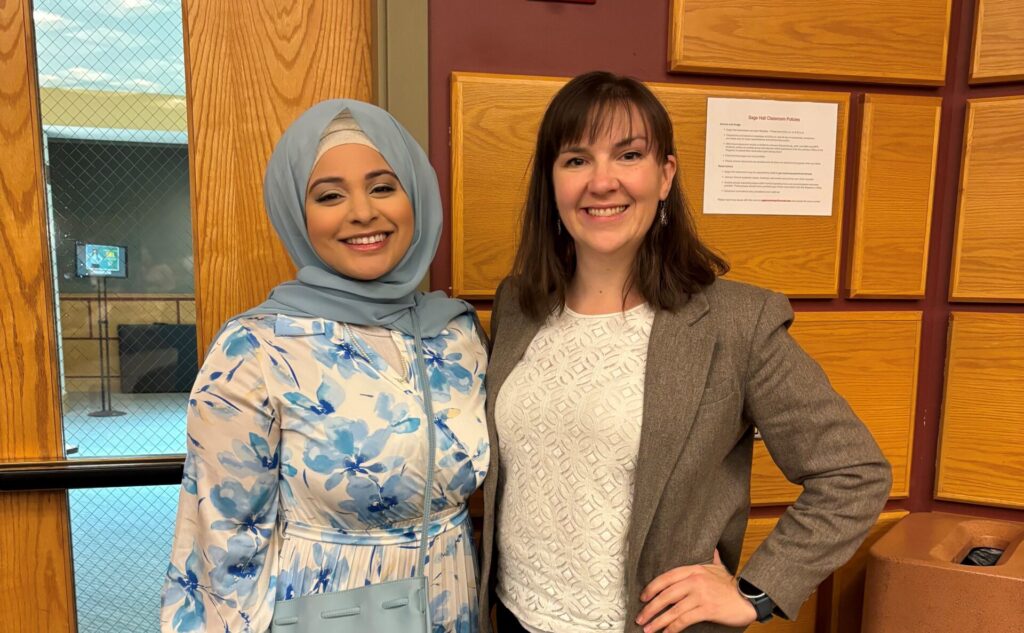 Two women stand together smiling at the camera.