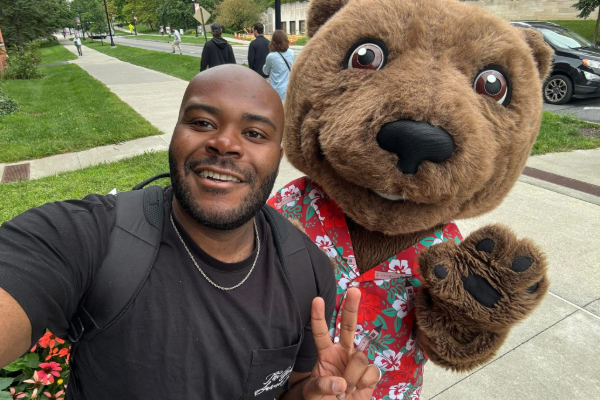 Image of Guy-Lee King, MBA ’26 outside of Sage Hall with the Cornell mascot, Touchdown