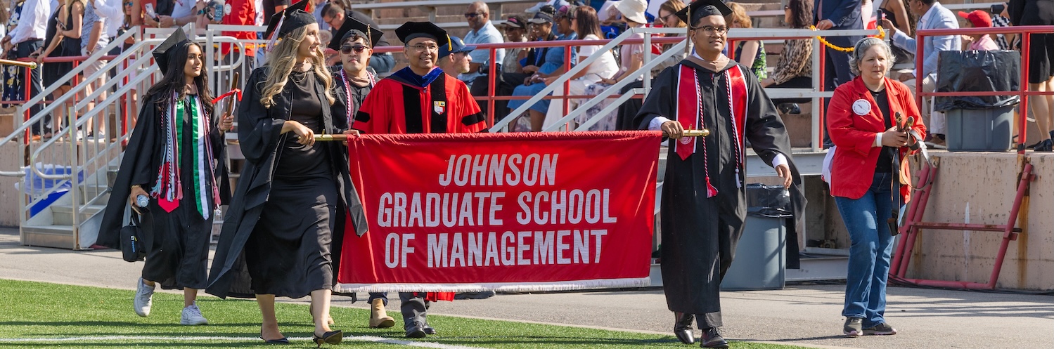 2024 Johnson graduate commencement banner bearers walking onto the field.