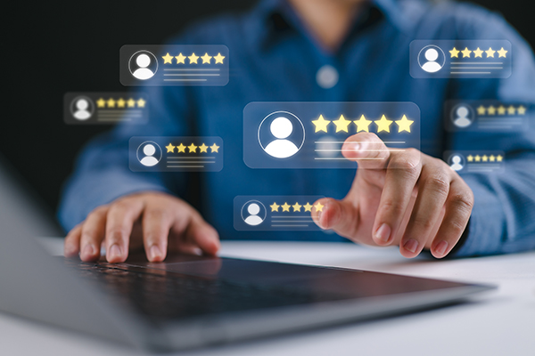 A blurred image of a person using a laptop with consumer ratings and stars floating